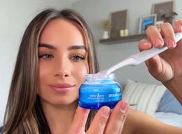 Woman holding the PurelyWHITE jar and dipping her toothbrush into the powder